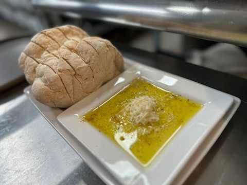 A loaf of bread and a bowl of olive oil on a plate.
