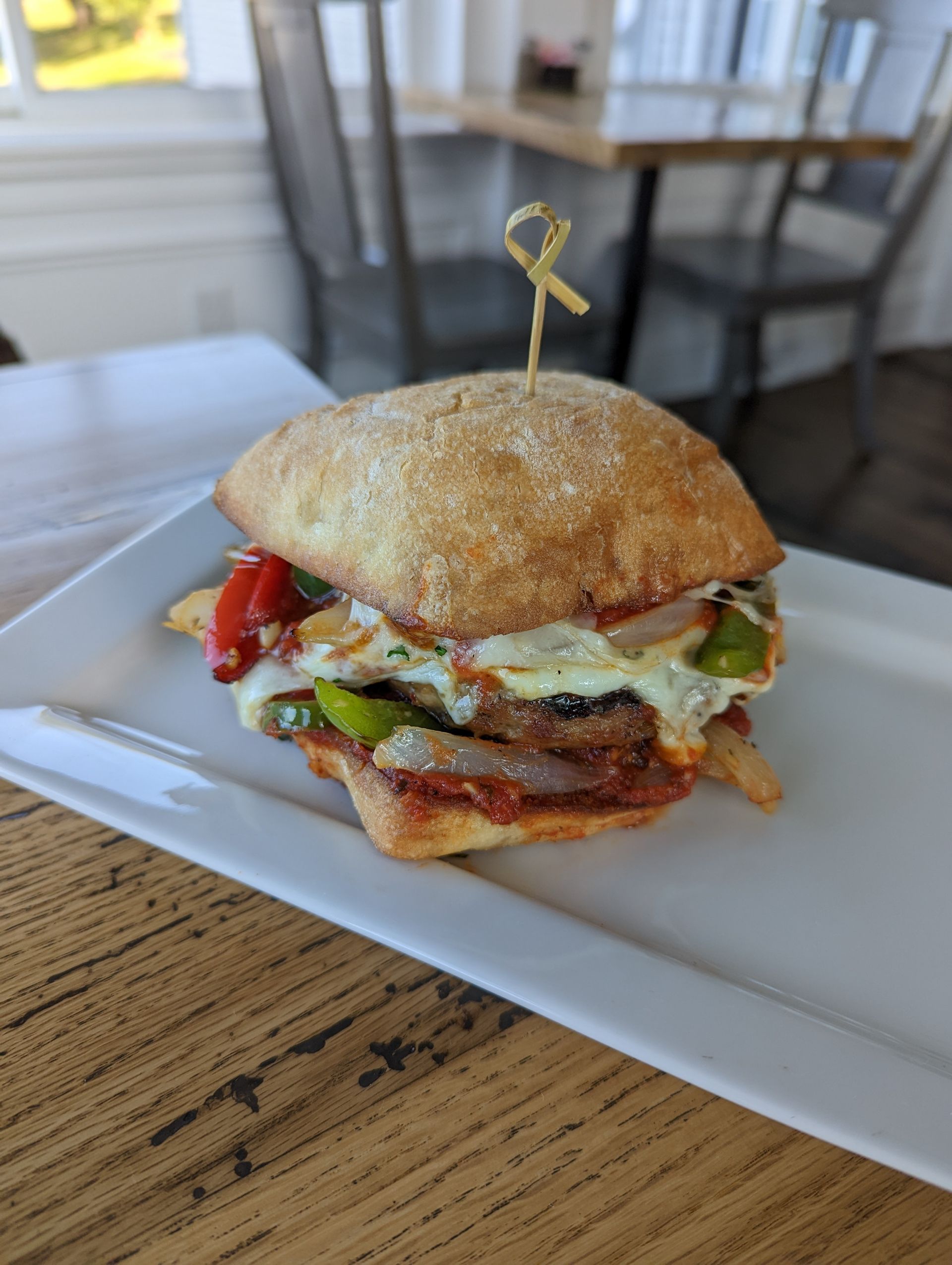 A sandwich is sitting on a white plate on a wooden table.