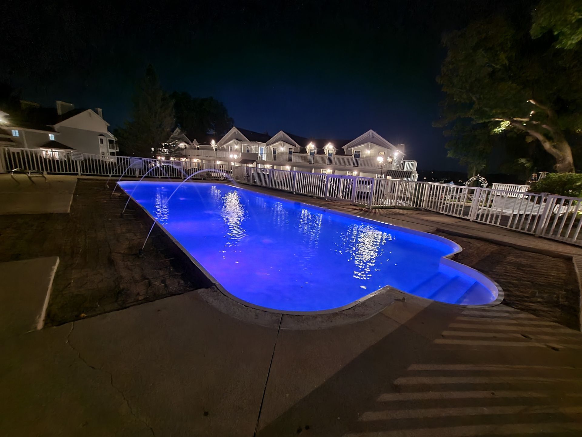A large swimming pool is lit up at night.
