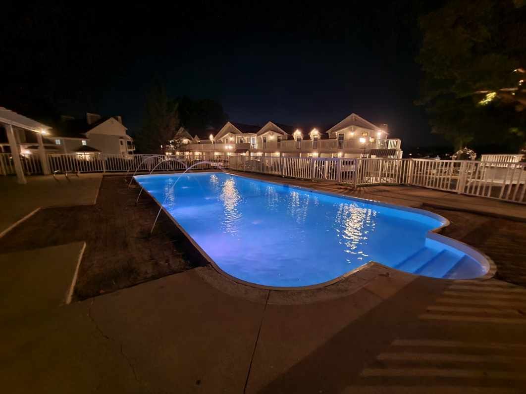 A large swimming pool is lit up at night.