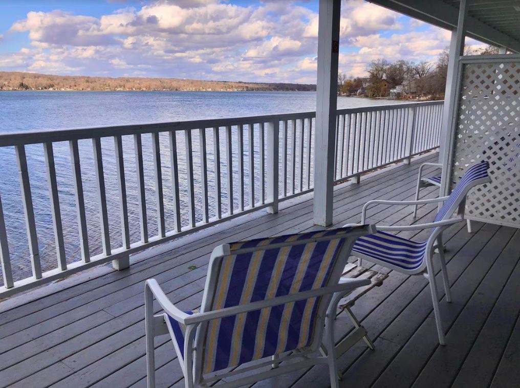A deck with chairs and a railing overlooking a body of water.
