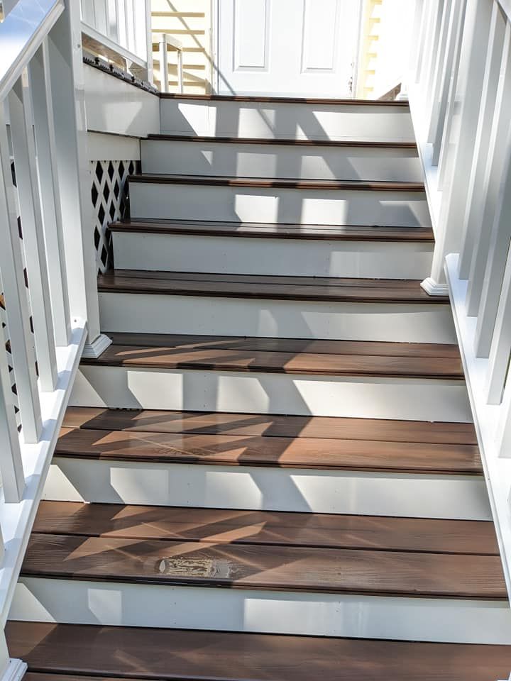 A set of wooden stairs with a white railing