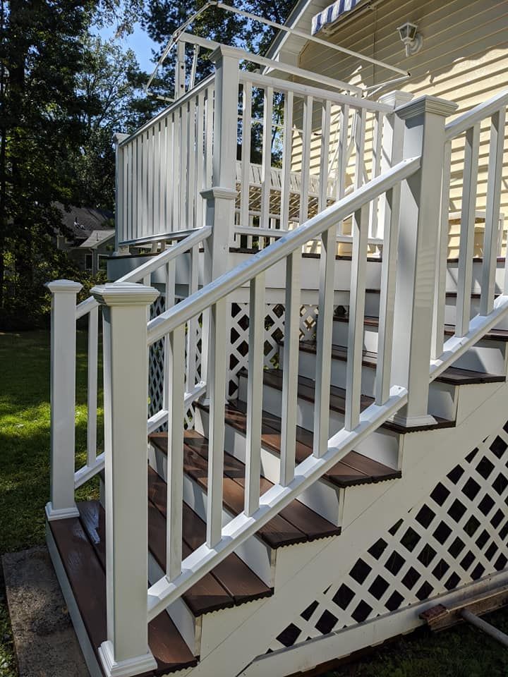 A set of stairs leading up to a deck with a white railing.