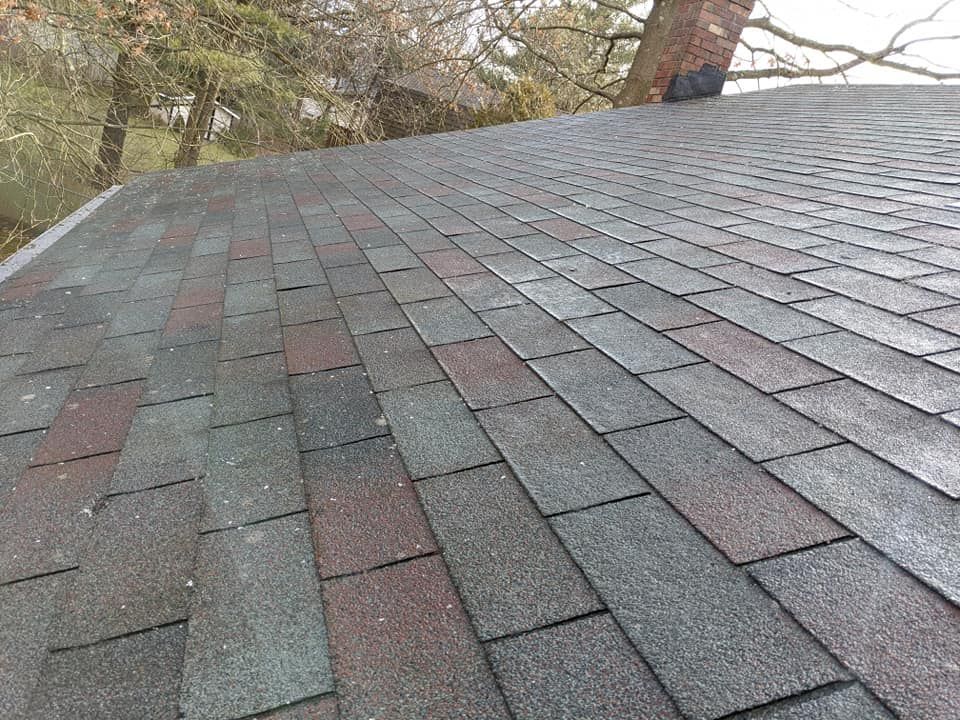 A man is cleaning a brick roof with a high pressure washer.