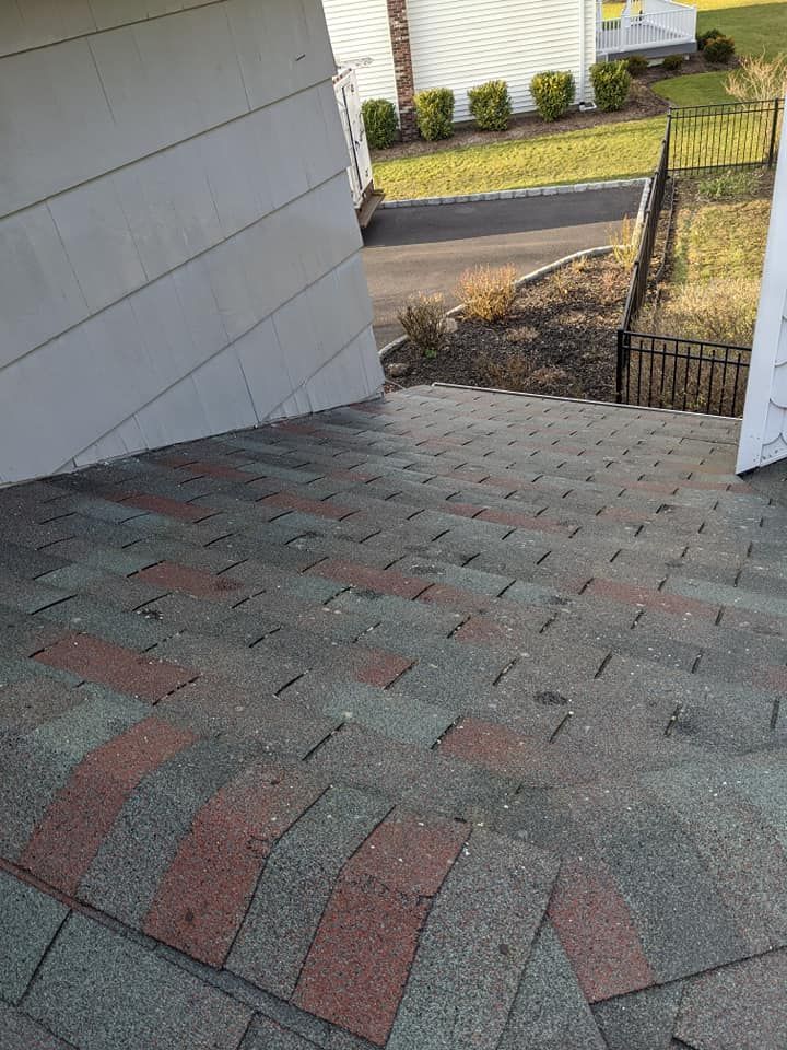 A man is cleaning a roof with a high pressure washer.