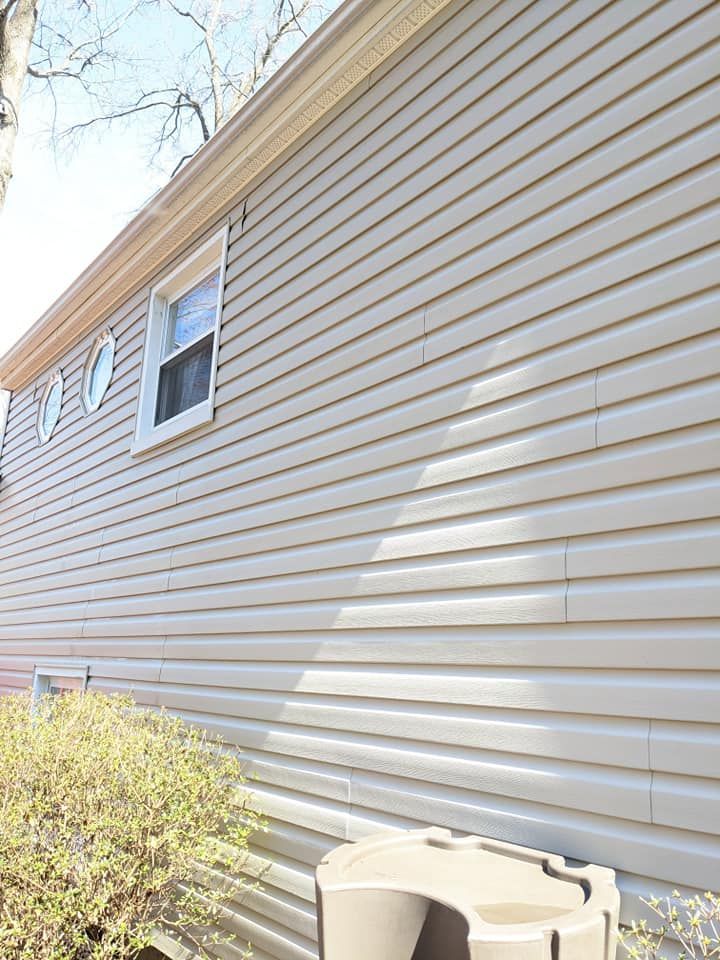 A white house with a trash can on the side of it.
