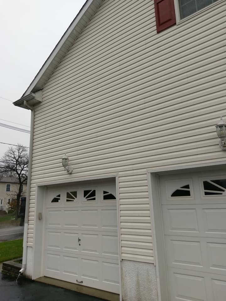 A white house with two white garage doors on a cloudy day.