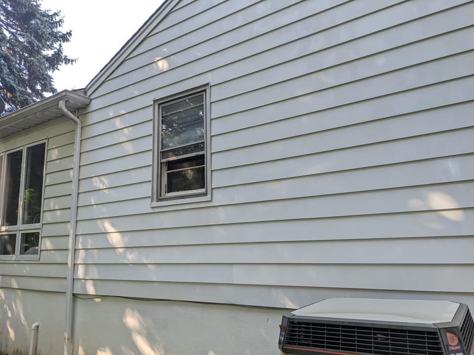 A white house with a window and an air conditioner on the side.