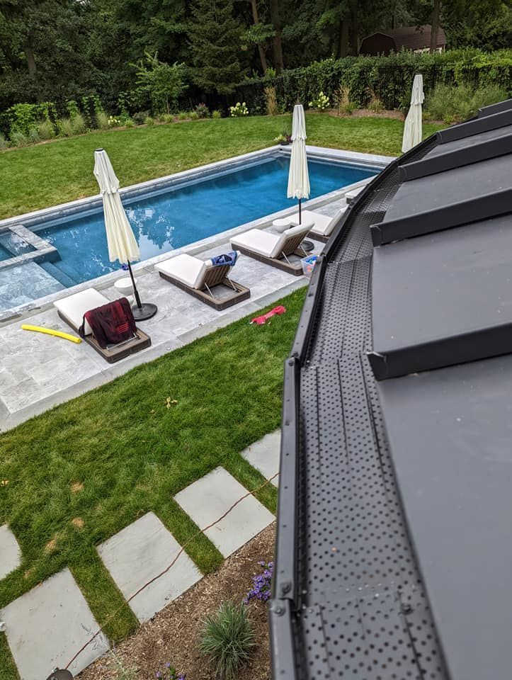 An aerial view of a swimming pool with chairs and umbrellas in a backyard.