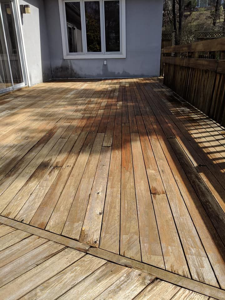 A wooden deck in front of a house with a window.