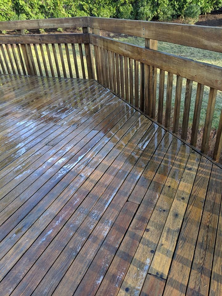 A wooden deck with a railing and trees in the background.