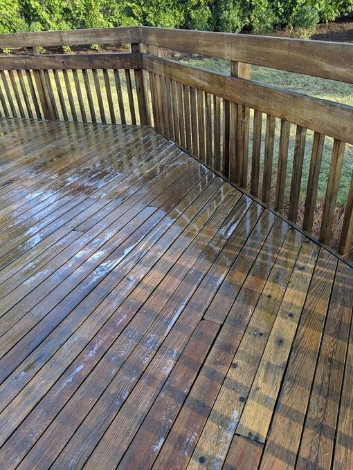A wooden deck with a railing and trees in the background.