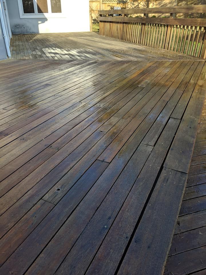 A wooden deck with a fence in the background and a house in the background.