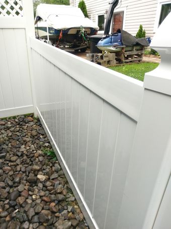 A white fence with a boat in the background