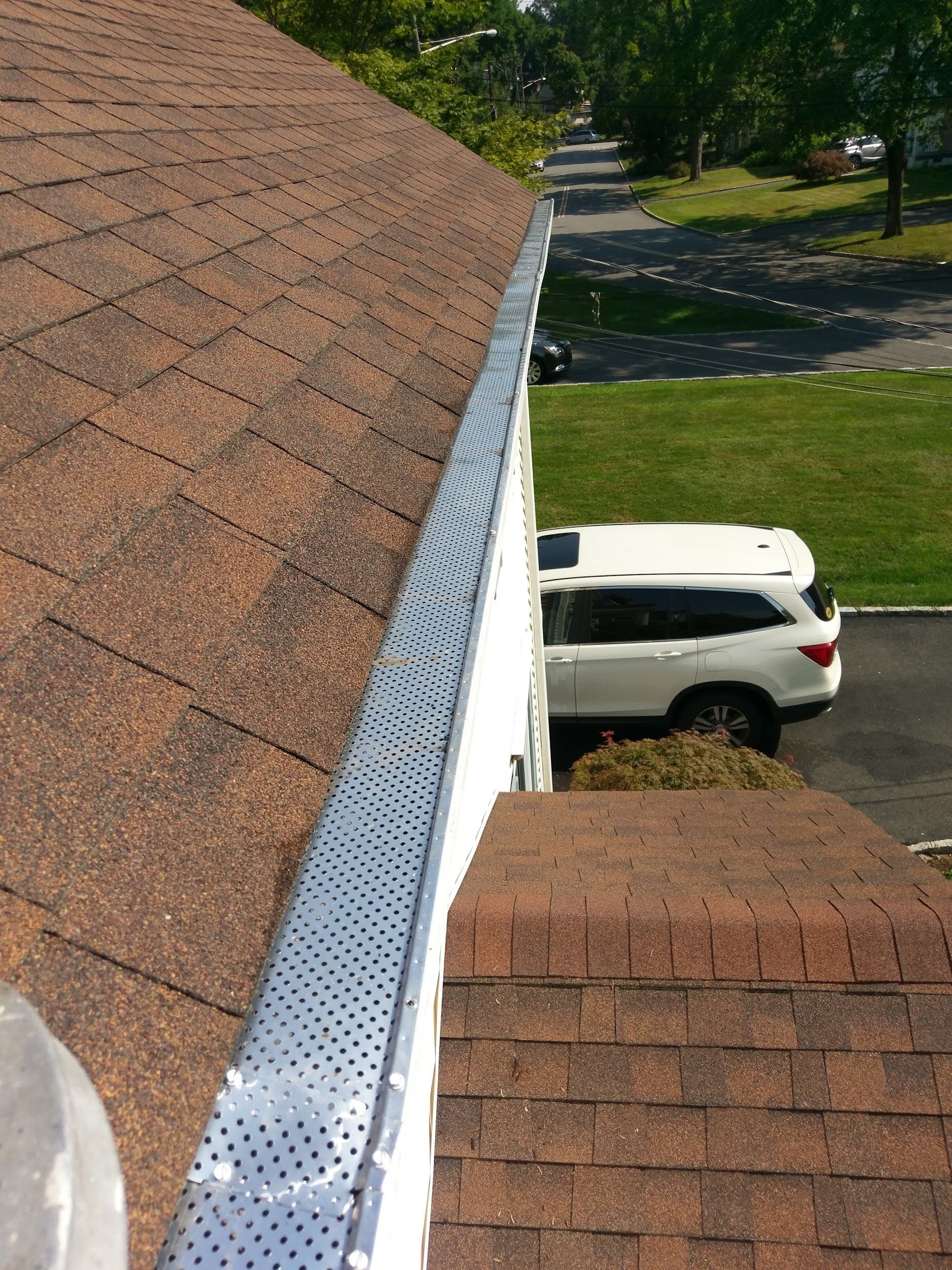 A car is parked on the side of a roof next to a gutter.