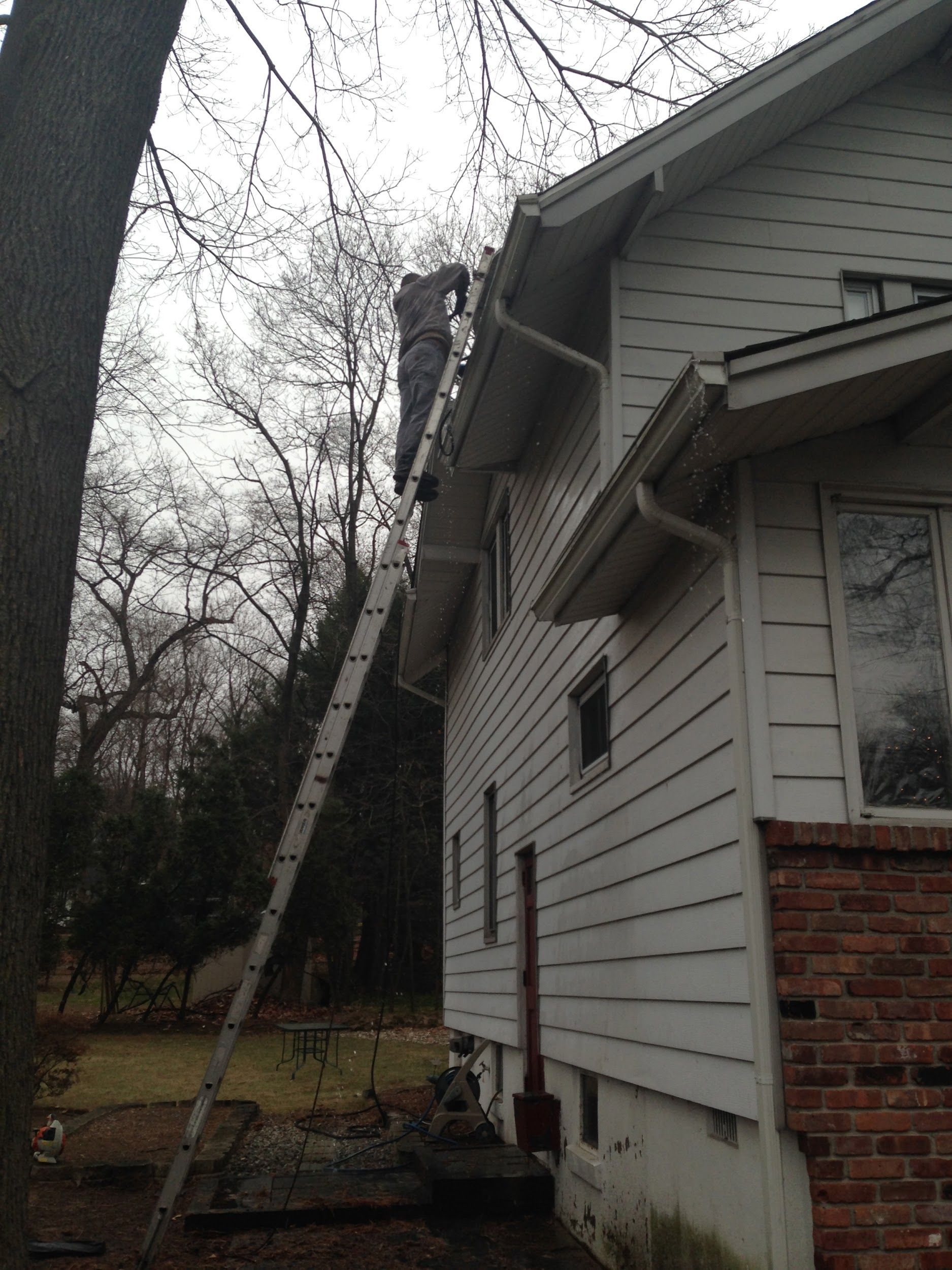 A man is standing on a ladder on the side of a house