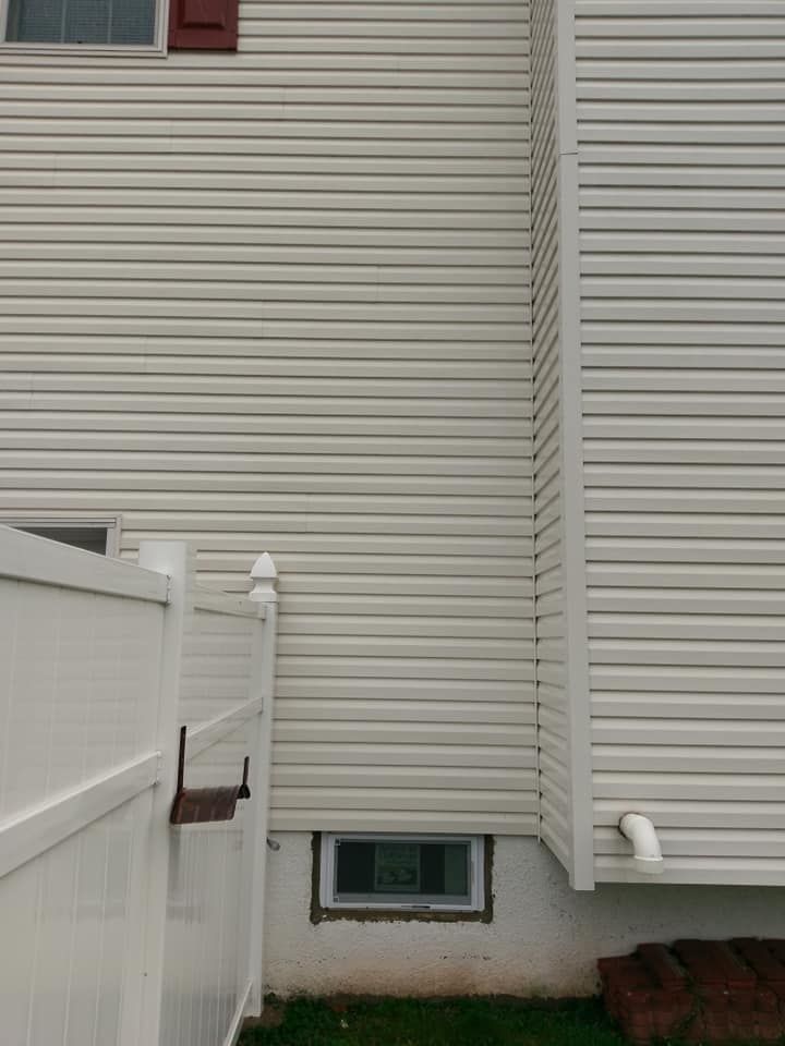 A white house with a white fence and a window in the corner.