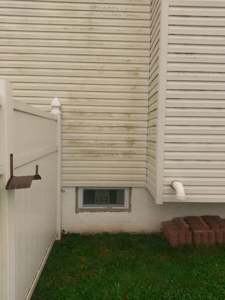A house with a white fence and a window in the backyard.