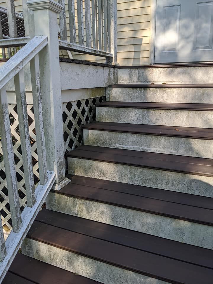A set of wooden stairs leading up to a house with a white railing.