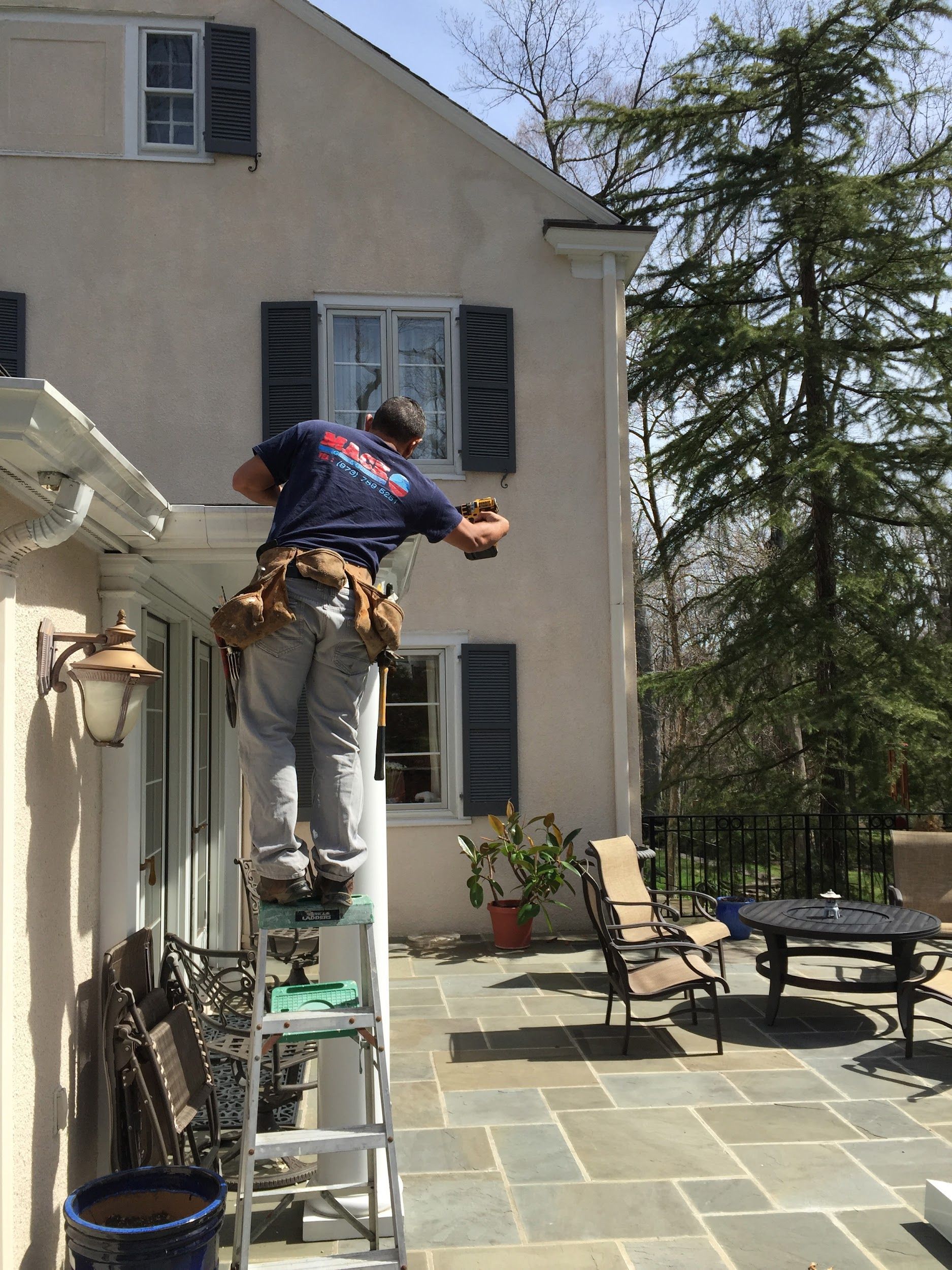A man is standing on a ladder in front of a house.