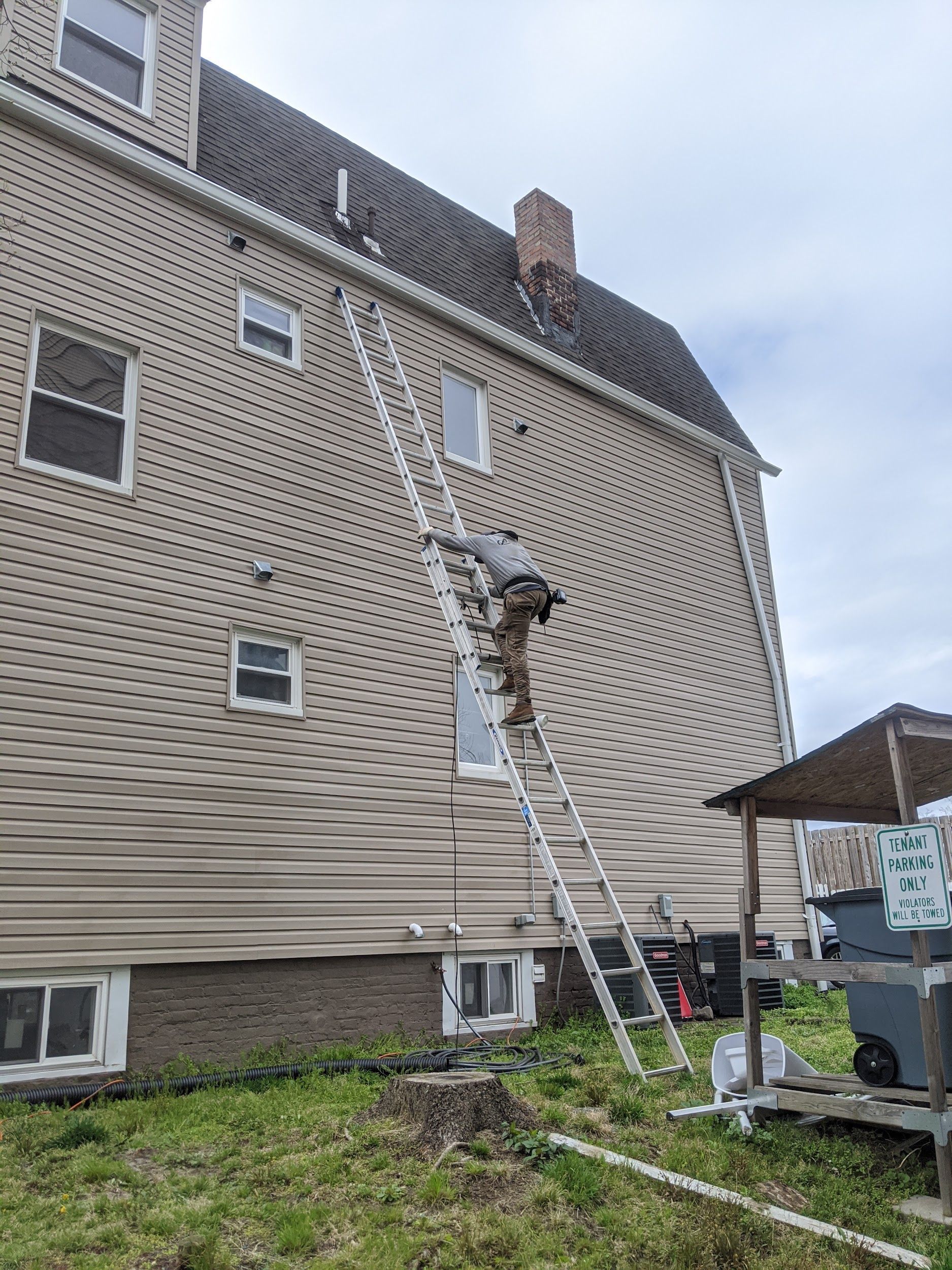 A man is standing on a ladder on the side of a house.