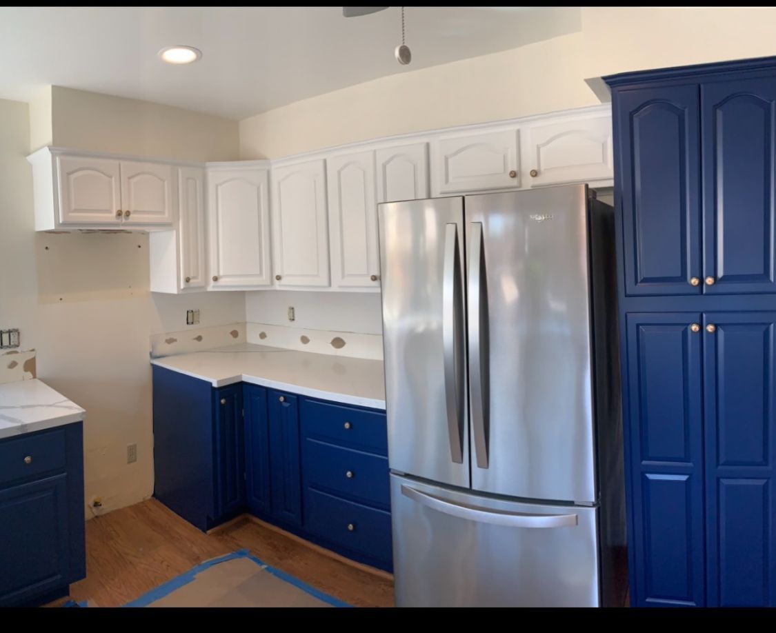 Empty room with deep blue wall, dark wood floor, white doors, and exposed wood ceiling beams