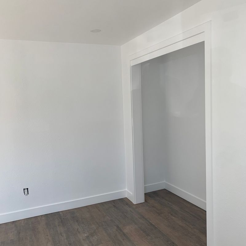 Empty white room with wood flooring and a large open closet doorway
