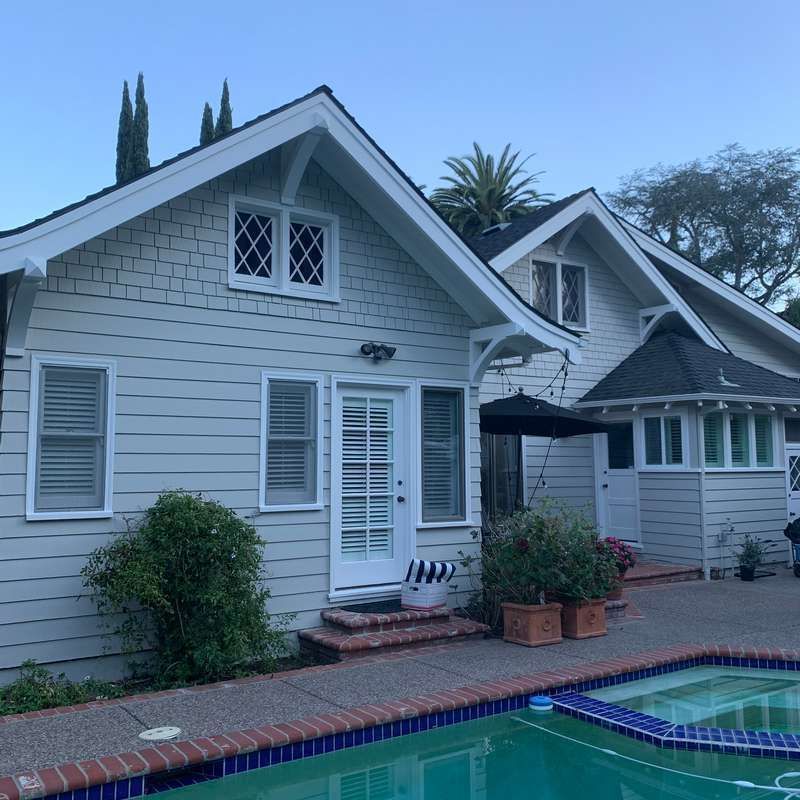 Gray house with white trim beside a blue-tiled pool at dusk