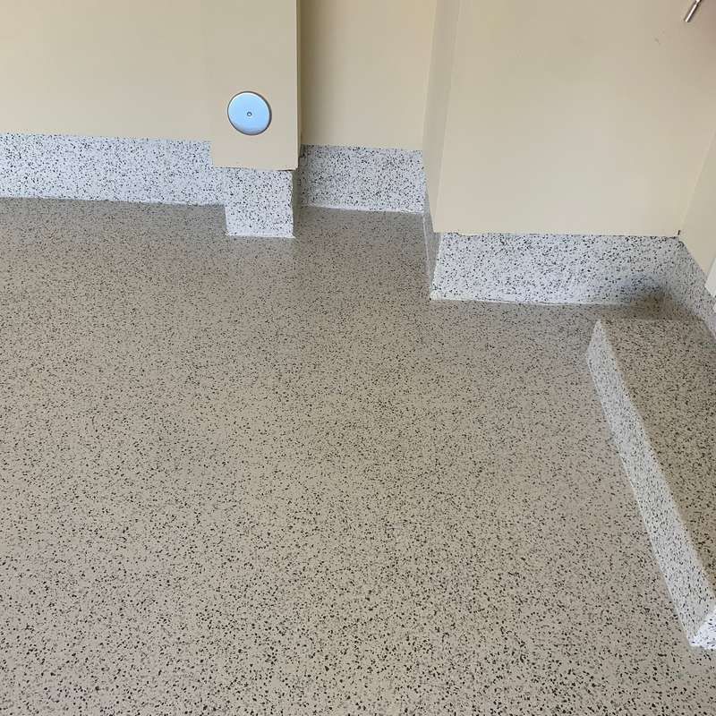 Speckled beige floor beside a beige wall with baseboard trim and a white corner marker.