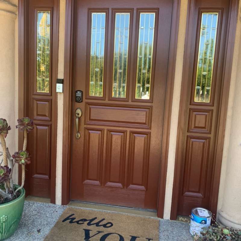Front door with glass panels, flanked by sidelights, and a “hello” doormat on the porch.