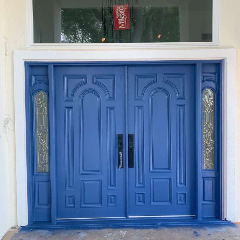 Blue double front doors with decorative glass panels in a white entryway