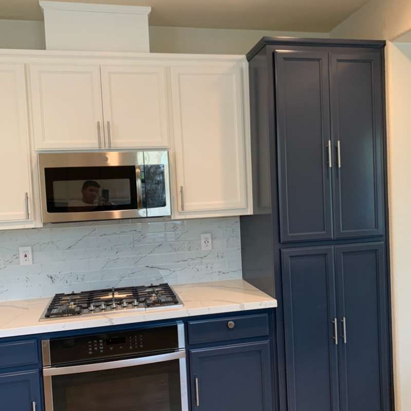 Modern kitchen with white upper cabinets, navy lower cabinets, stainless microwave, and gas cooktop