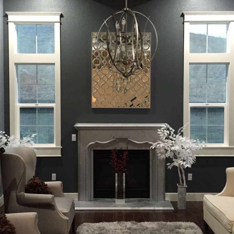 Elegant living room with dark walls, white fireplace, chandelier, and tall windows