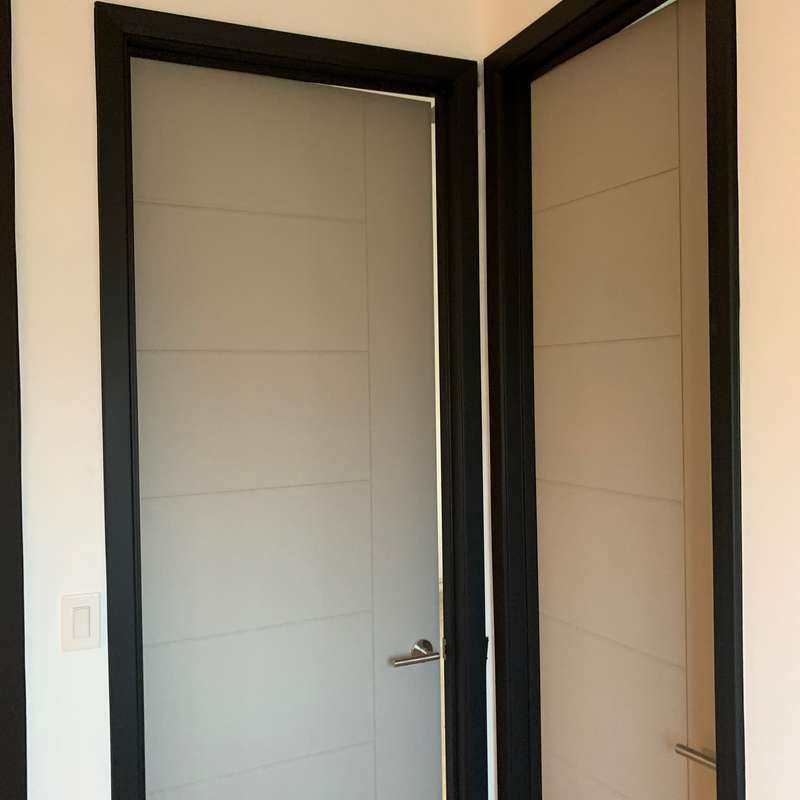 Two closed interior doors with black trim in a beige hallway