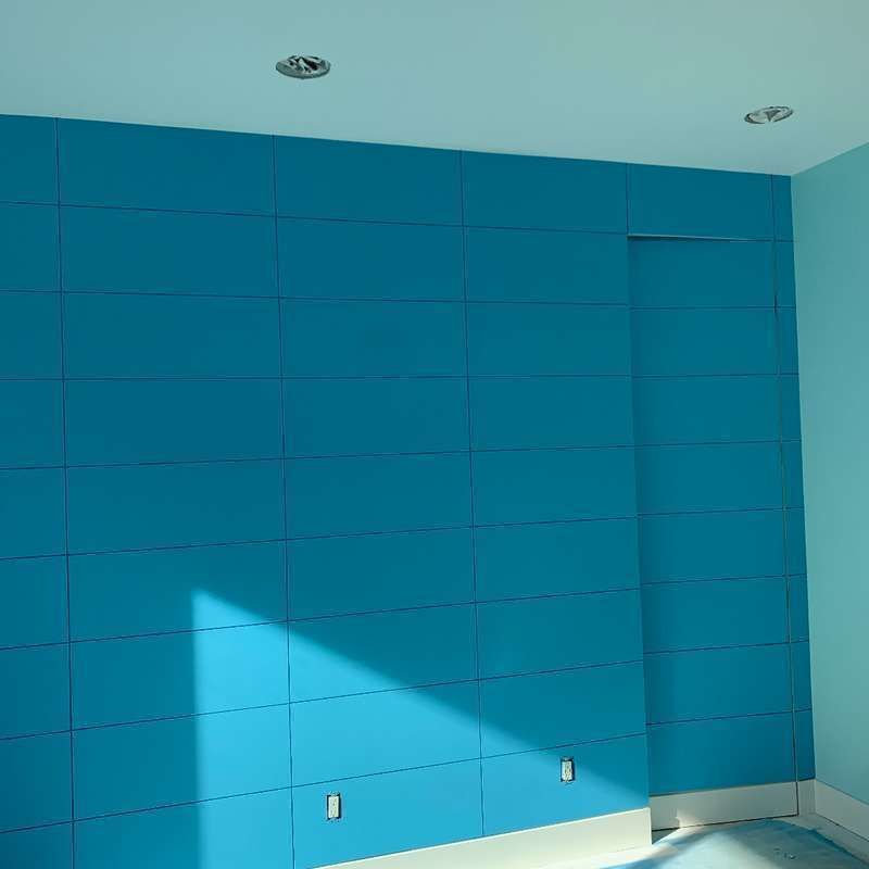 Empty room with a bright blue accent wall and sunlight casting a triangular shadow