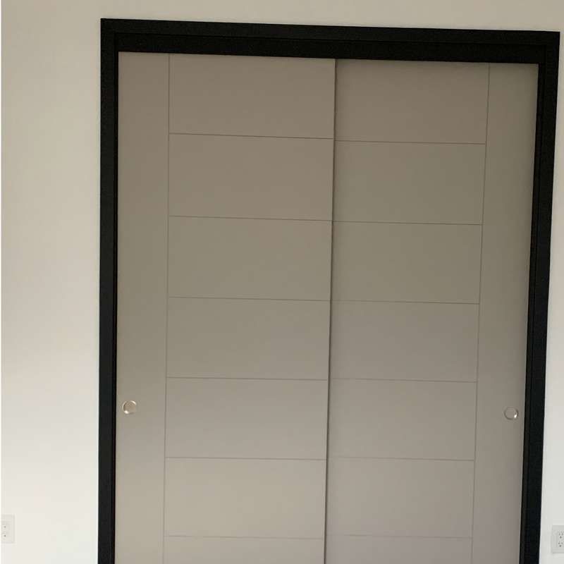 Black-framed sliding closet door with light gray panels in a white room.