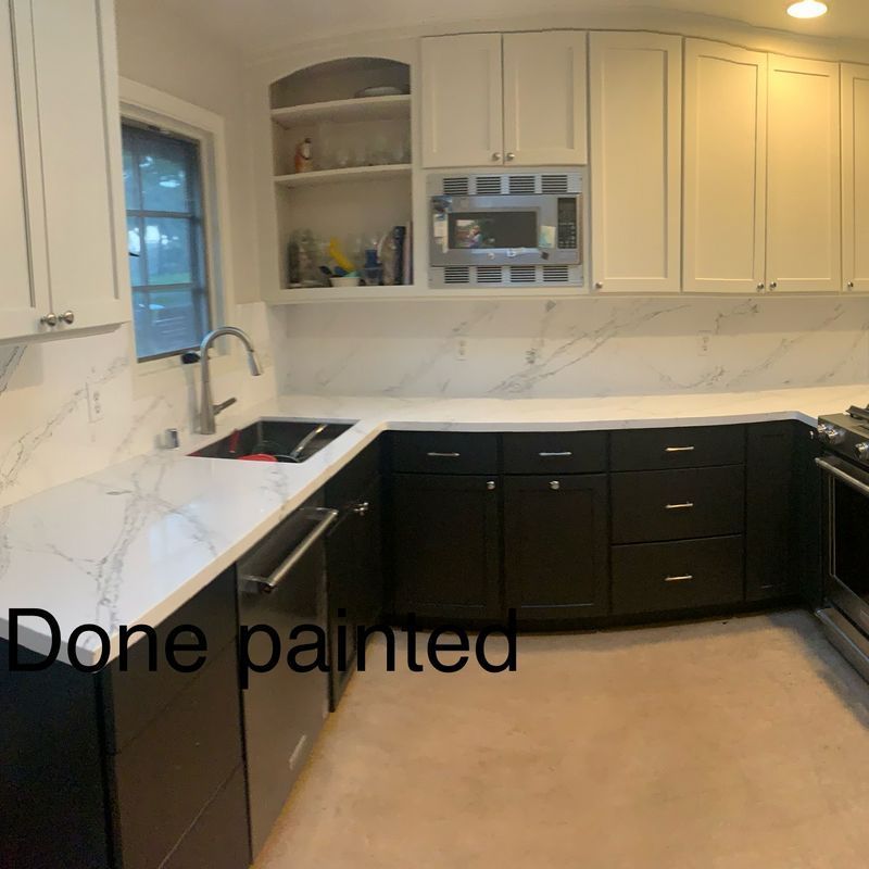 Kitchen with white cabinets, dark lower cabinets, marble backsplash, and text reading “Done painted”