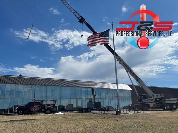 A large crane is lifting a flag in front of a large building.