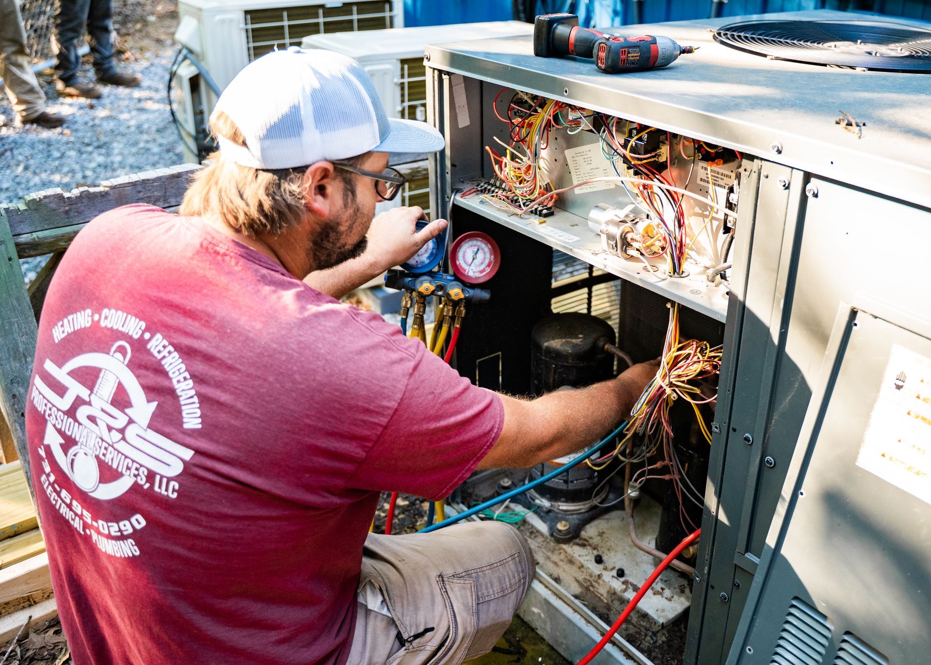 A man is working on an air conditioner with a pressure gauge.