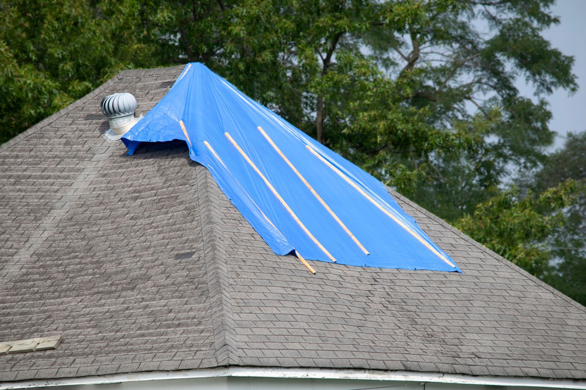 A blue tarp is covering the roof of a house.