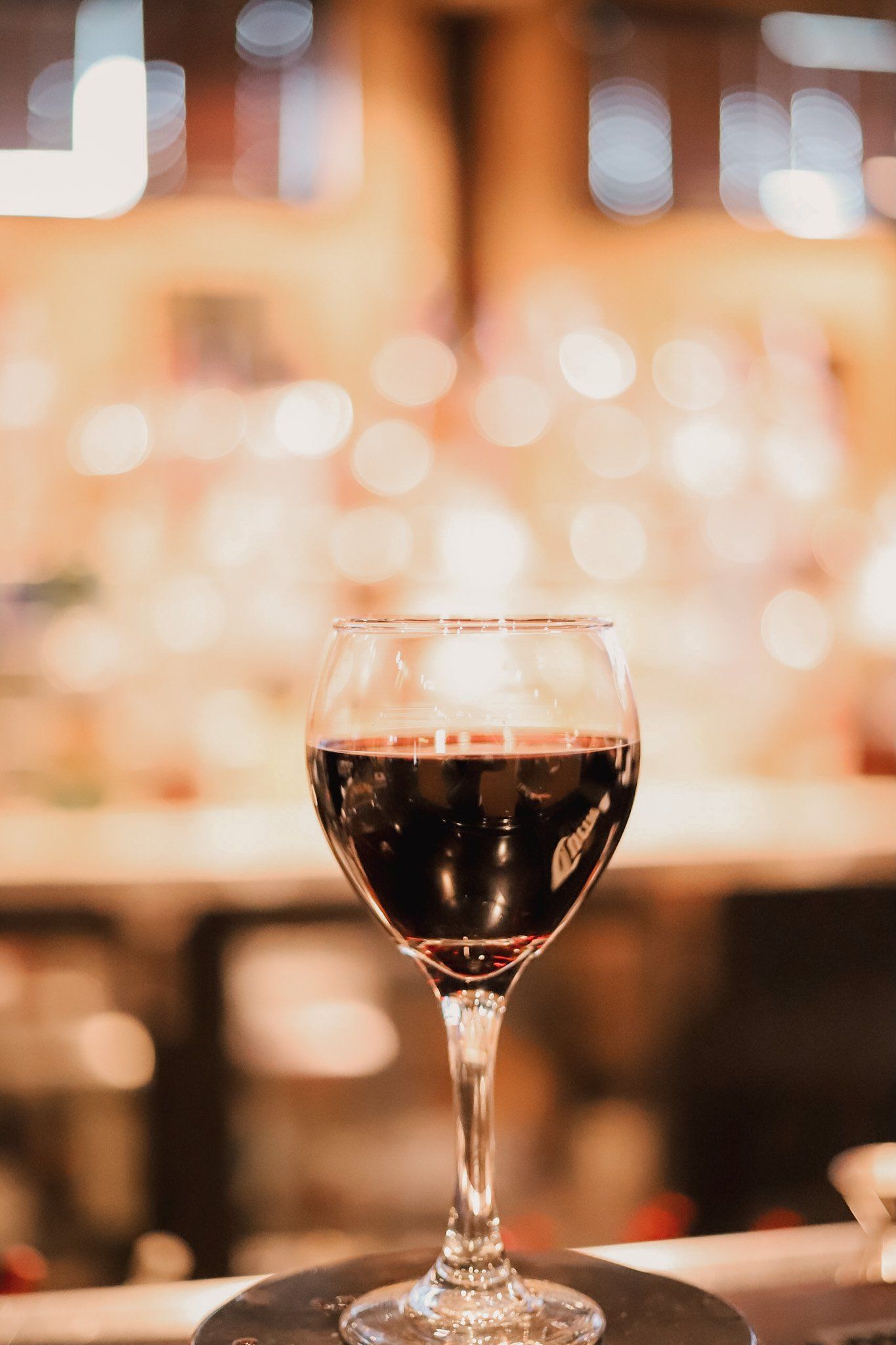 A glass of red wine is sitting on a table at authentic smokehouse barbecue