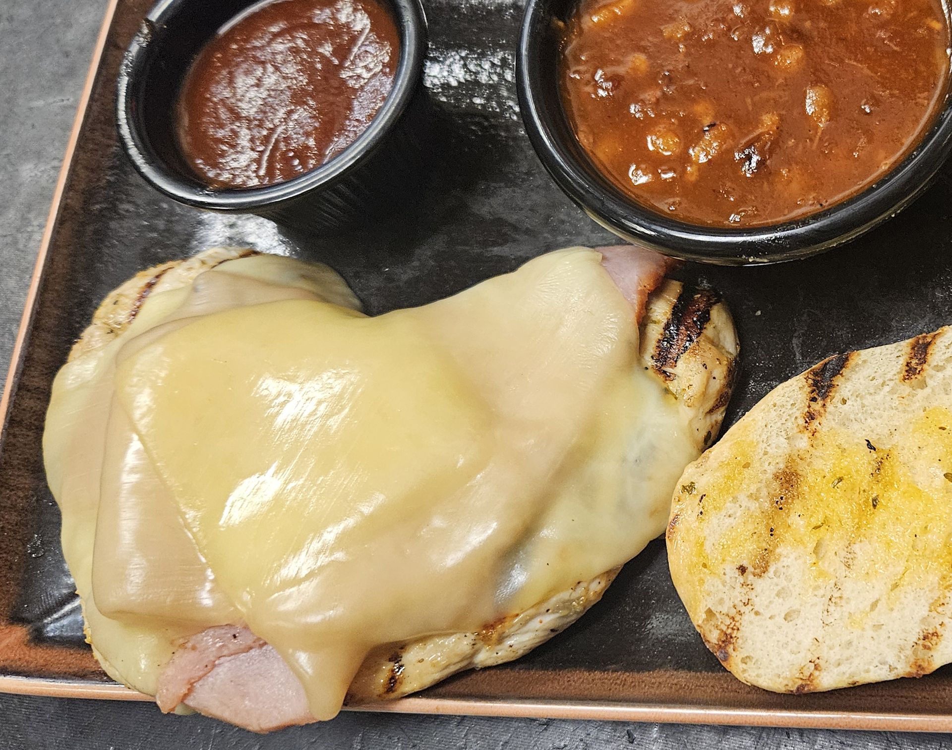 A chicken sandwich with french fries and a bowl of beans on a plate - Smokehouse bbq kansas city