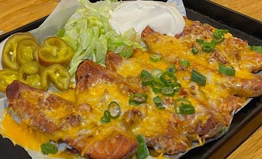 Independence Mo plate of food with cheese , lettuce and jalapenos on a table.