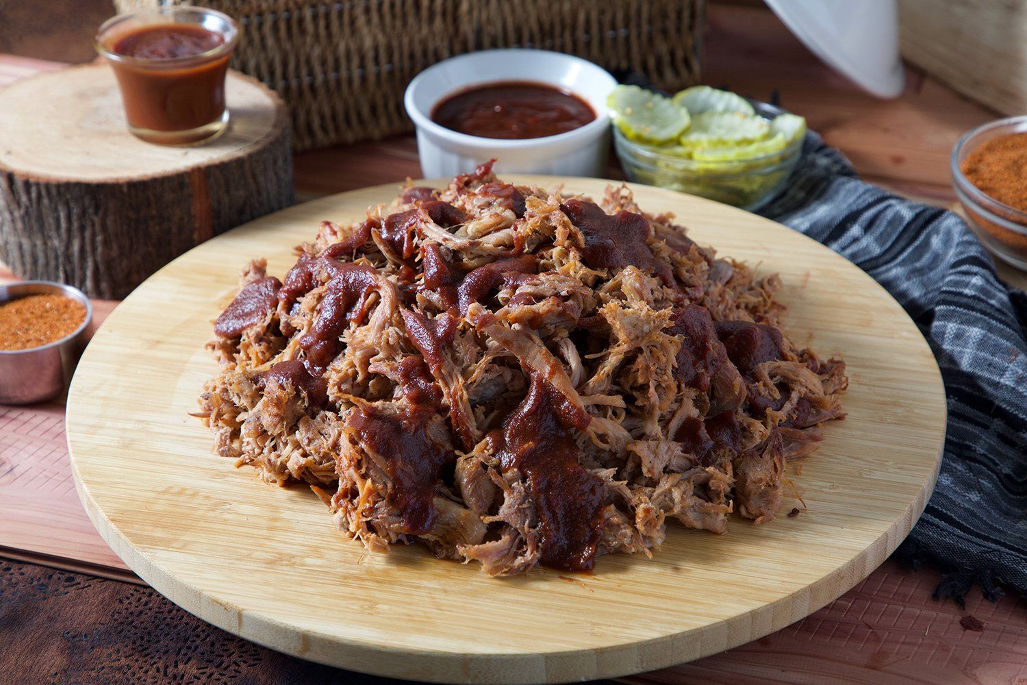 Smokehouse bbq wooden cutting board topped with pulled pork and barbecue sauce.