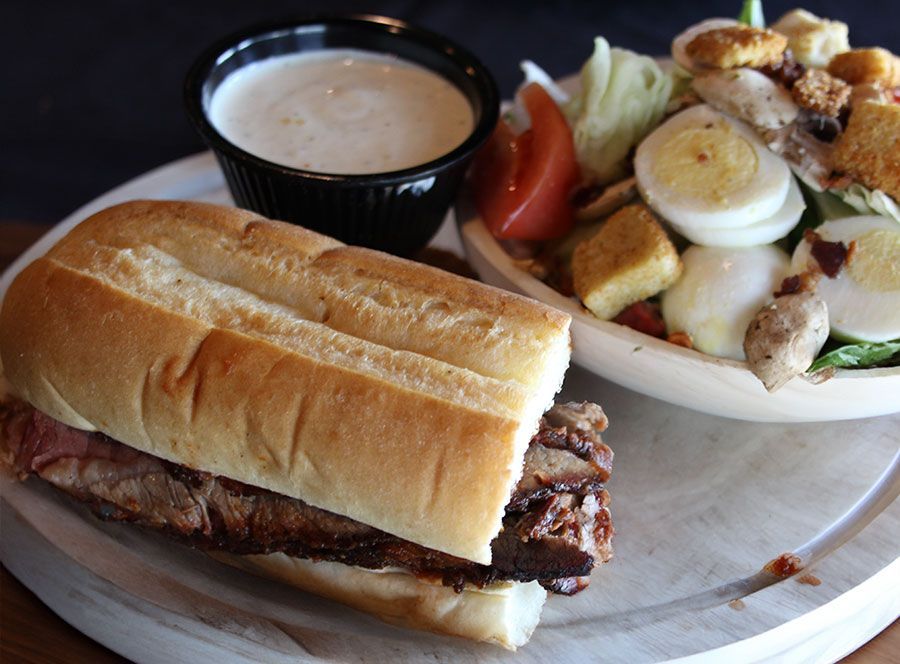 Smoked beef sandwich with salad and ranch dressing at authentic smokehouse barbecue restaurant