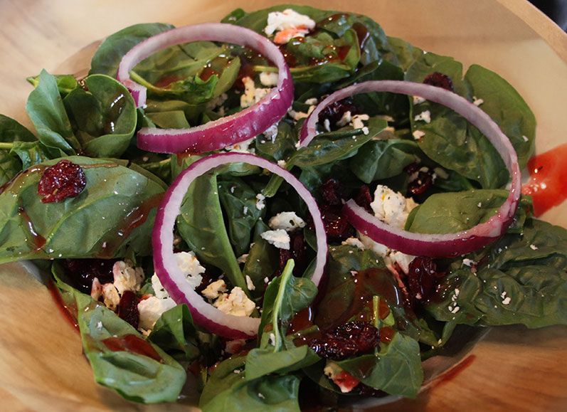 A salad with spinach onions and feta cheese on a white plate at authentic smokehouse bbq
