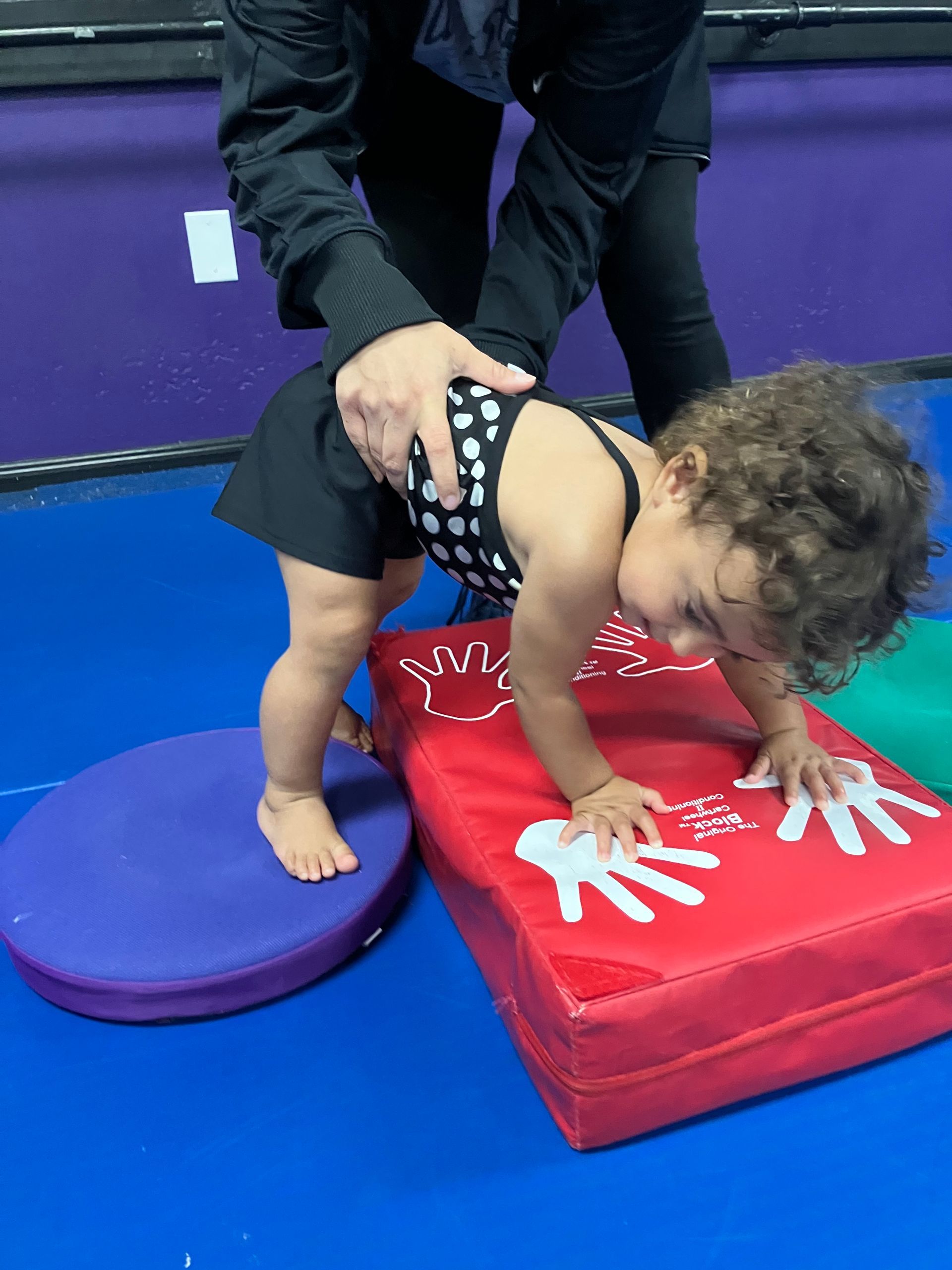 A little girl is doing a handstand on a mat.