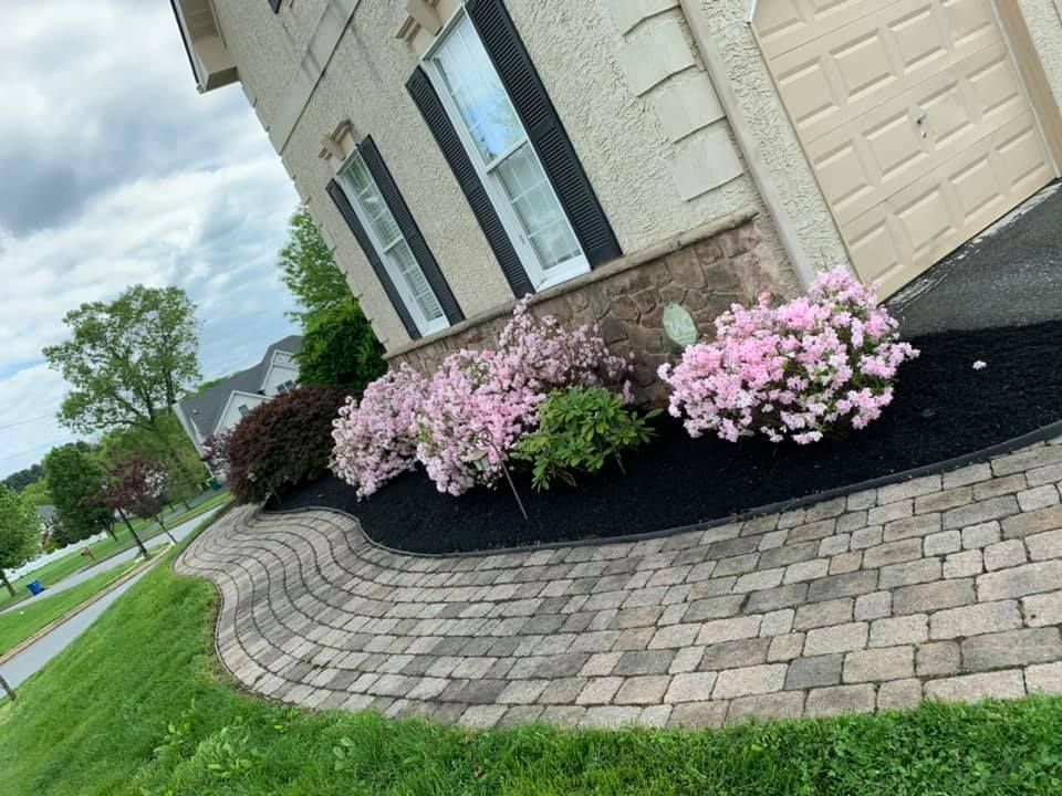 A stone fire pit with a flickering flame sits in the center of a flagstone patio surrounded by cushioned wicker chairs.