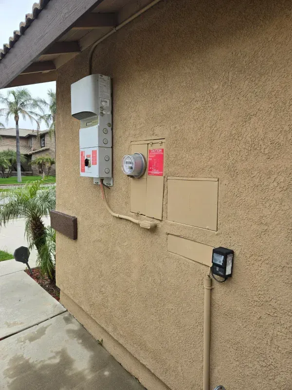 Tan stucco exterior with a meter box, electrical equipment, and a smaller black box.