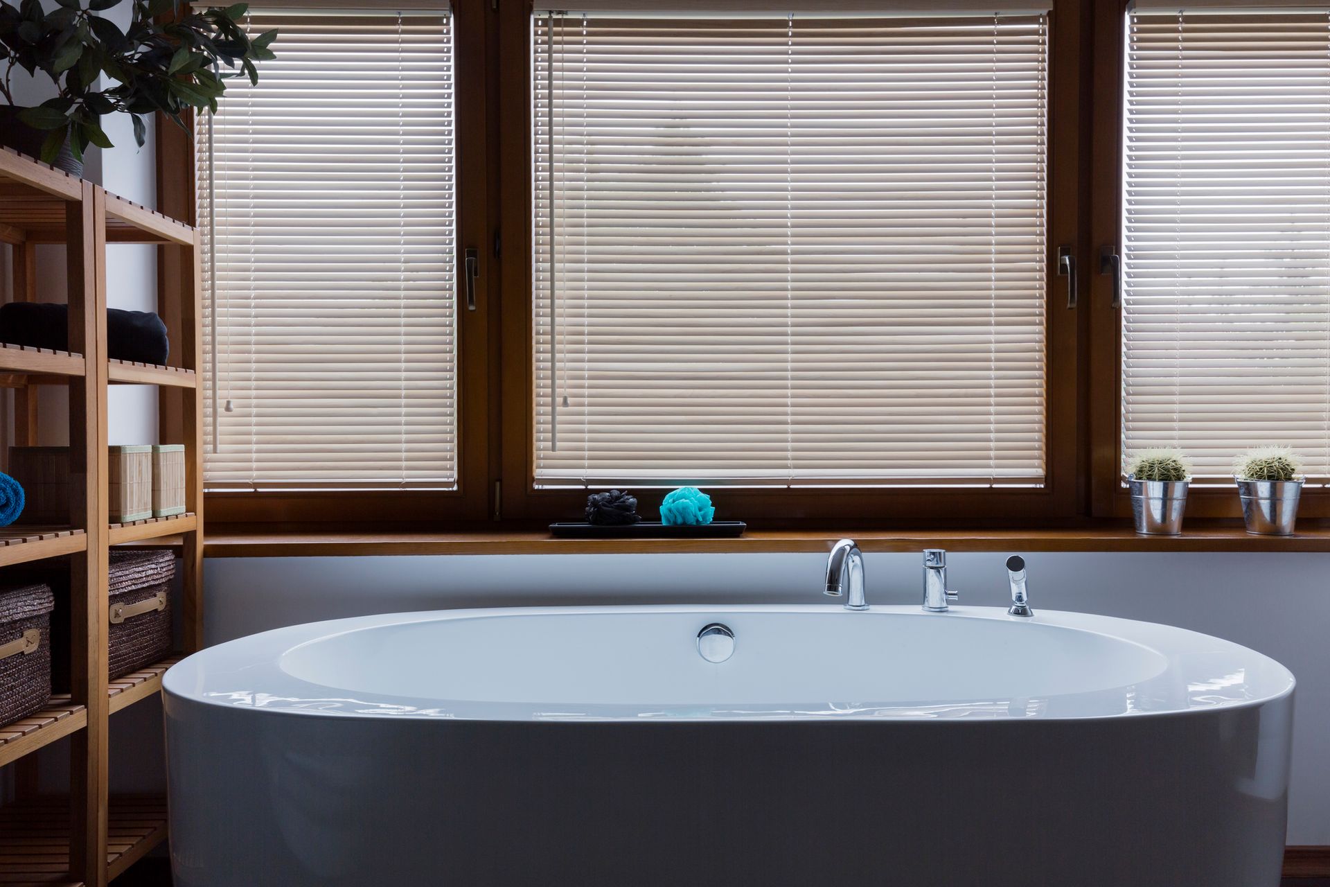 A bathroom with a bathtub and a window with blinds.